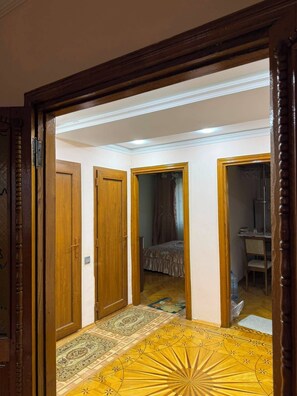 Ein Flur mit Holztüren, einem gemusterten Teppich und einem Bett im angrenzenden Zimmer.