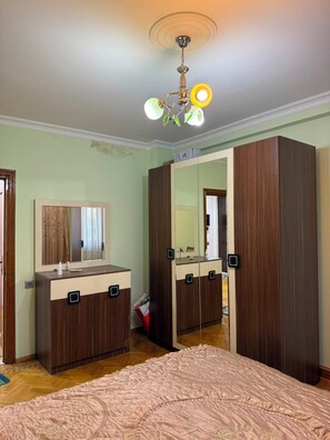 Een slaapkamer met een bed, een kledingkast, een spiegel en een plafondlamp.