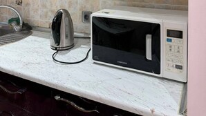 Una cocina con microondas, hervidor y un mueble con diseño decorativo.