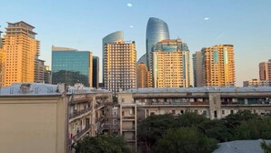 Vista de un paisaje urbano con edificios altos, incluyendo un rascacielos de diseño curvo, tomada desde un balcón.