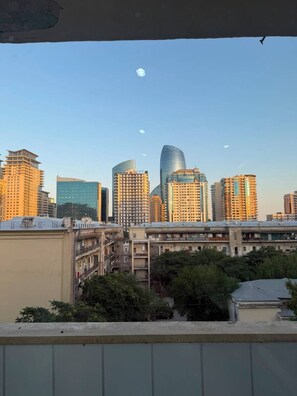 A cityscape with high-rise buildings, including a distinctive curved skyscraper, viewed from a balcony.