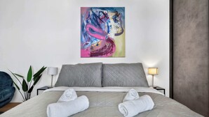 A hotel room with a bed, pillows, a painting, a lamp, and a plant. - Design & Panoramic View - Central BA (Bratislava-Staré Mesto)