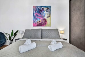 A hotel room with a bed, pillows, a painting, a lamp, and a plant. - Design & Panoramic View - Central BA (Bratislava-Staré Mesto)