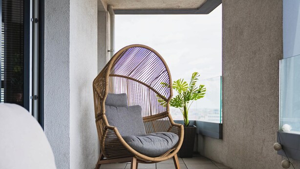 A wicker chair with a cushion, a potted plant, and a view of the cityscape. - Design & Panoramic View - Central BA (Bratislava-Staré Mesto)