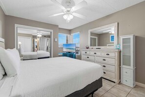 A bedroom with a bed, a dresser, a mirror, and a ceiling fan. - Waterfront Condo with shared pool & fitness room (Fort Walton Beach)