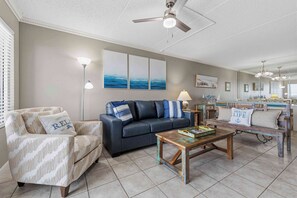 A living room with a sofa, armchair, coffee table, and artwork on the wall. - Waterfront Condo with shared pool & fitness room (Fort Walton Beach)