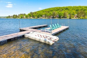 Ein Steg mit Stühlen und einer schwimmenden Plattform in einem See.