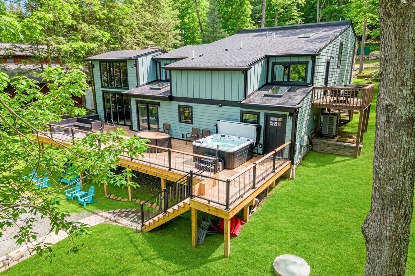 Una casa de dos pisos con terraza, jacuzzi y zona de estar al aire libre.