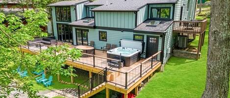Una casa de dos pisos con terraza, jacuzzi y zona de estar al aire libre.