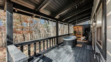 A wooden deck with a hot tub and a wooden structure with a bench.