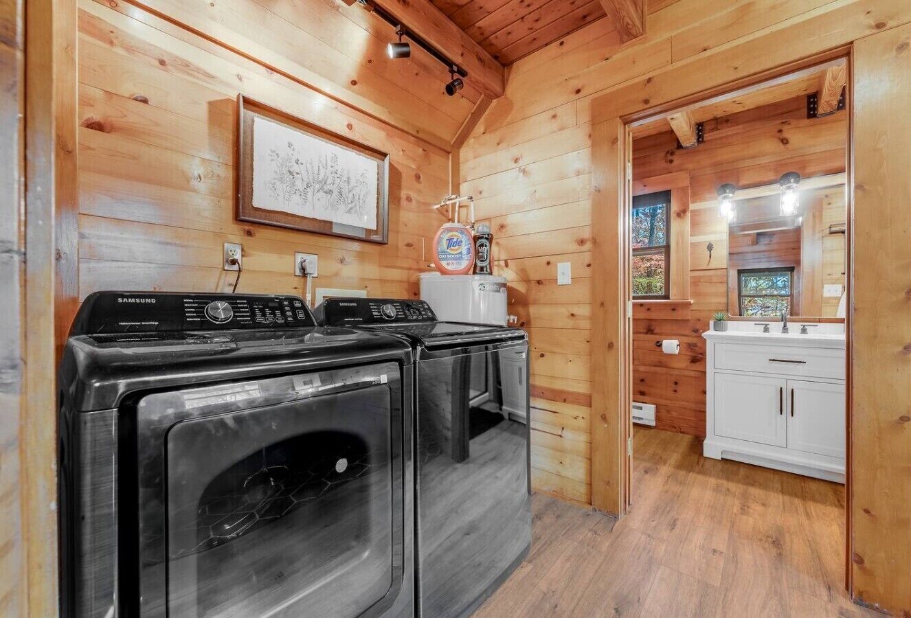 A laundry area with two washing machines and a dryer, a sink, and a cabinet.