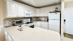 A kitchen with white cabinets, a microwave, a stove, a dishwasher, and a refrigerator. - OV 123 Tennis Court View - Welcome To Paradise! (Fort Pierce)