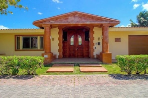 A building with a central entrance, a covered porch, and a paved driveway. - Beachfront Villa | Private Chef, Pool & Transfer (Playa del Carmen)
