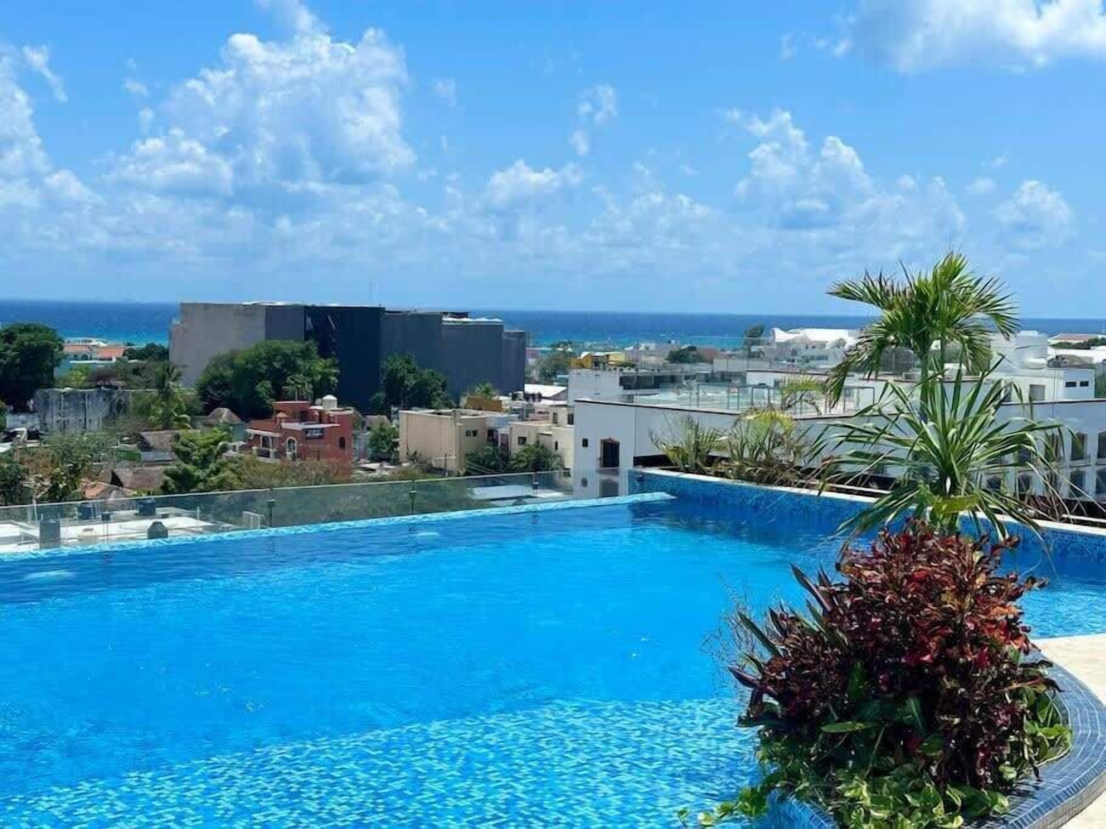 An infinity pool with a clear view of the ocean and buildings in the background.