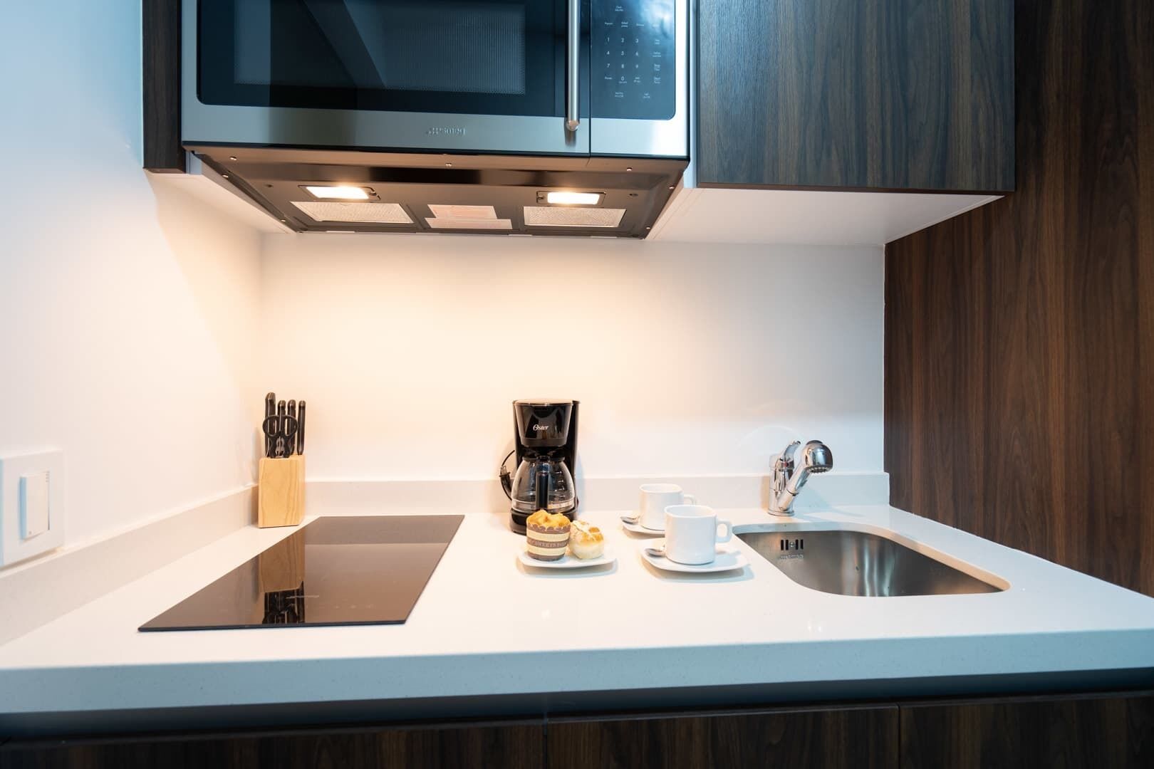 A modern kitchen with a built-in microwave, coffee maker, and stainless steel sink.