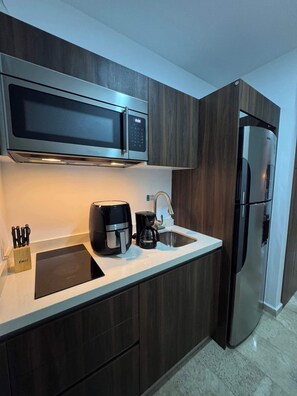 A modern kitchen with a built-in microwave, coffee maker, and stainless steel refrigerator. - Ground-Floor Studio · Terrace & Rooftop Pool (Playa del Carmen)