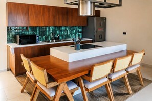 A modern kitchen with a central island, wooden cabinets, and a stainless steel refrigerator. - Villa Sol | 2BR Ocean View & Pool | Isla Mujeres (Isla Mujeres)