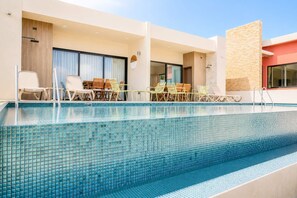 A modern hotel pool area with a clear pool, lounge chairs, and a covered seating area. - Villa Sol | 2BR Ocean View & Pool | Isla Mujeres (Isla Mujeres)