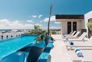 Ein Pool mit Rutschen, Liegestühlen und einem Gebäude mit Türen.