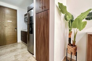 Een keuken met een inbouwkoelkast, houten kastjes en een potplant.