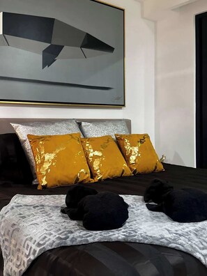 A bedroom with a large bed, a headboard, and a painting on the wall. - Chic Studio · Rooftop Pool · 1 Blk to 5th Ave (Playa del Carmen)