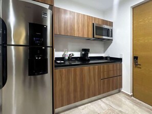 Eine Küche mit Edelstahlgeräten, Holzschränken, einer Mikrowelle und einer Kaffeemaschine.