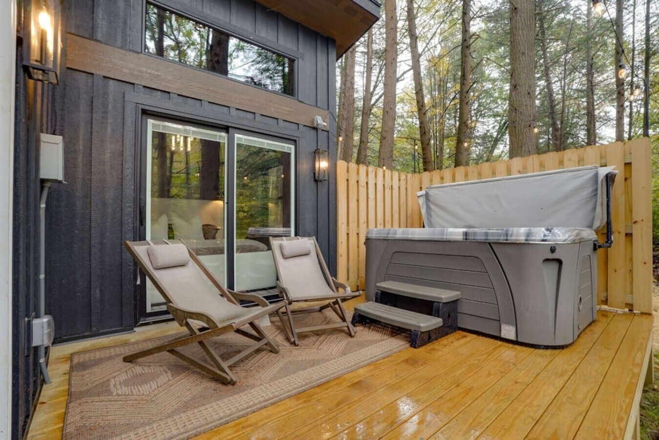 Una terraza con dos sillas reclinables, un jacuzzi y una valla de madera.