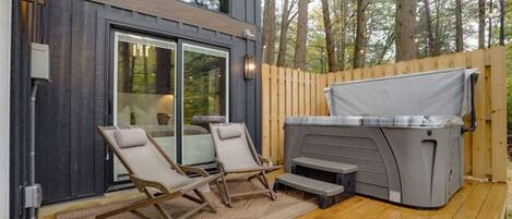 Una terraza con dos sillas reclinables, un jacuzzi y una valla de madera.