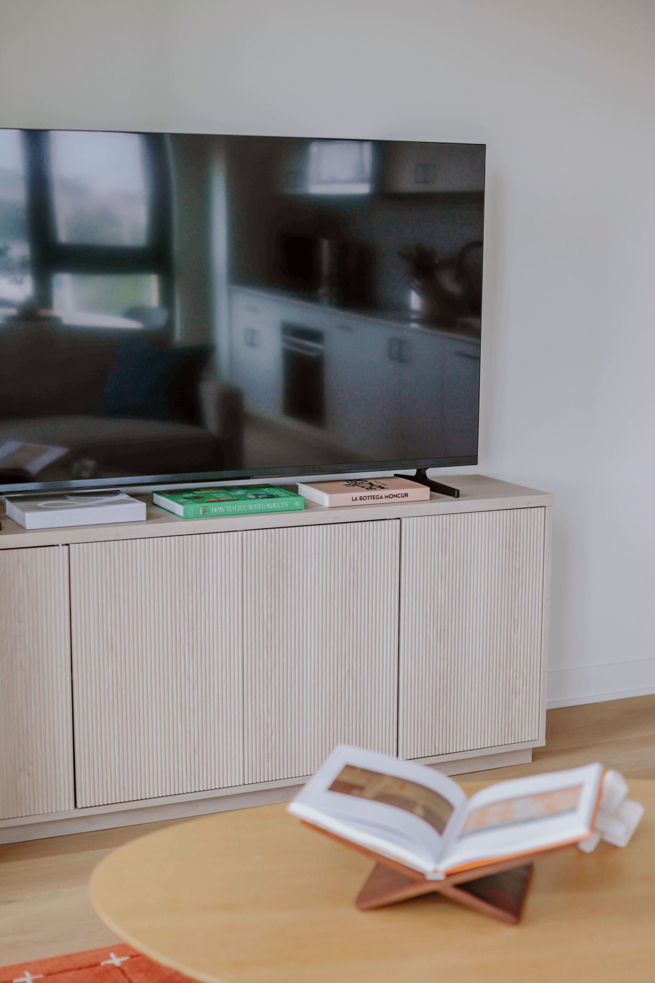 A flat-screen TV mounted on a wall above a white ribbed cabinet.