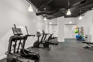 Ein Fitnessstudio mit Laufbändern, Crosstrainern und einem Bereich für Krafttraining.