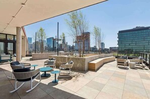 An outdoor seating area with modern furniture, a city view, and a clear sky. - Luxury Penthouse Collection PH2 - Fulton Market (Chicago)