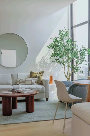 Ein modernes Wohnzimmer mit einer Couch, einem Couchtisch und einer Topfpflanze.