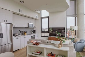 Eine moderne Wohnung mit Küche, Wohnbereich und großen Fenstern mit Blick auf die Stadt.