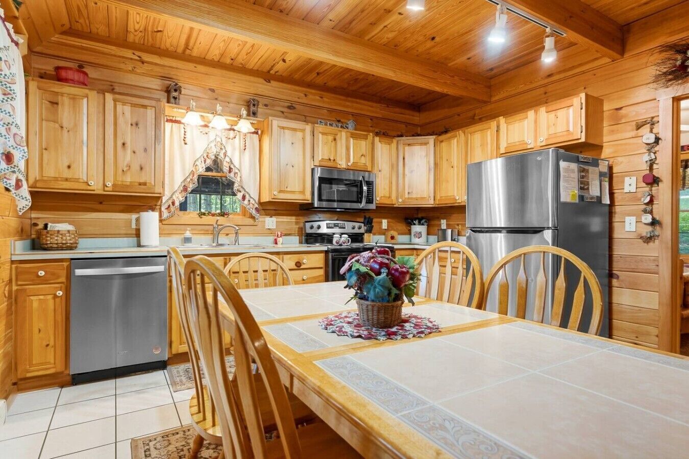 A wooden cabin-style kitchen with a dining table, chairs, a refrigerator, a microwave, and a stove.
