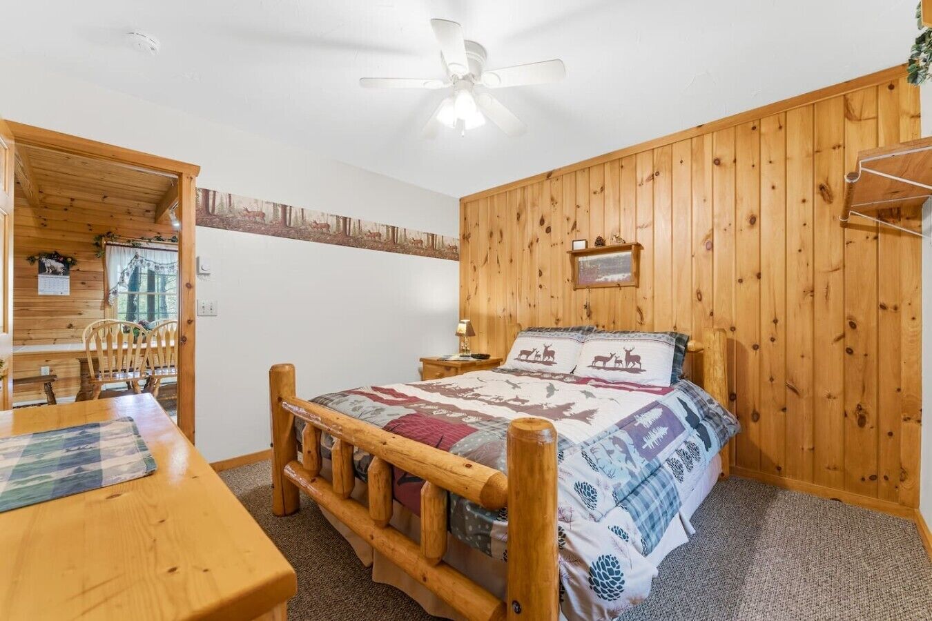 A wooden-paneled bedroom with a bed, a wooden desk, and a chair.