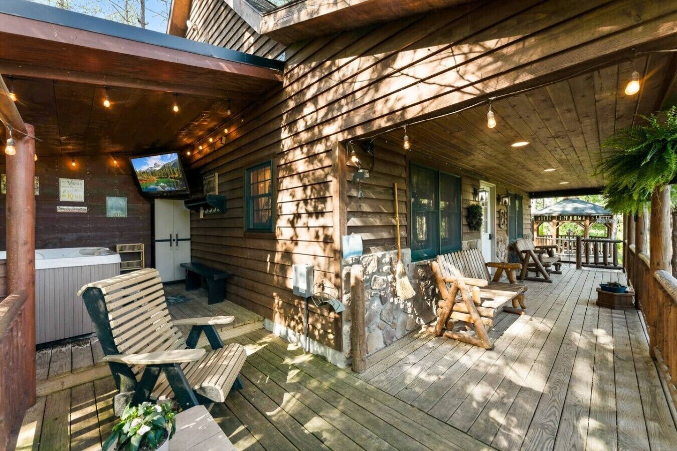 Uma cabana de madeira com varanda coberta, área de estar externa e hidromassagem.