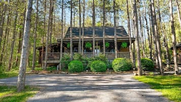 Een chalet met een veranda, omgeven door bomen.