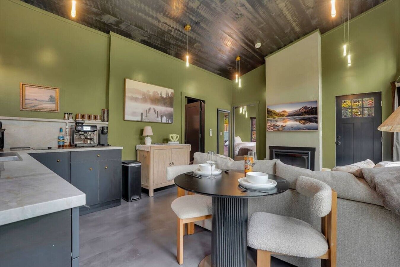 A modern kitchen with a dining area, a sofa, and a fireplace.