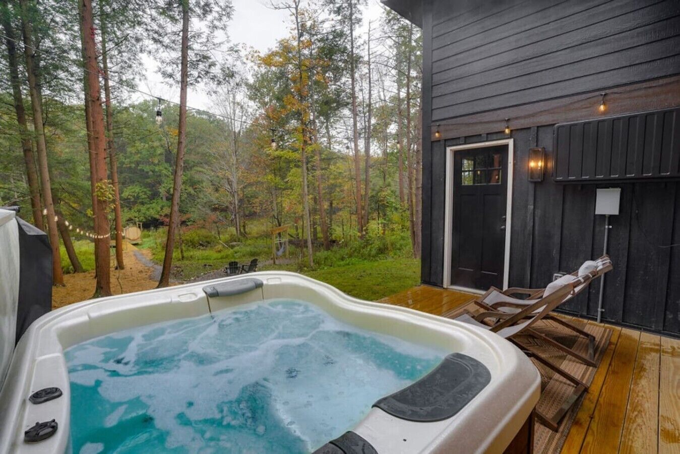 Een hottub op een houten terras met uitzicht op het bos.