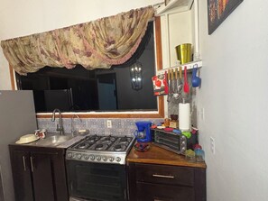 A kitchen with a gas stove, sink, and a window with a curtain. - Cottage with a pool and natural surroundings—just 20 minutes from the beaches and Manuel Antonio Park! (Naranjito)