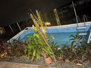 Piscina cercada por plantas e uma escada.