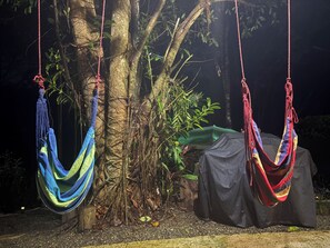 Two hammocks suspended from a tree, a covered table, and dense foliage in the background. - Cottage with a pool and natural surroundings—just 20 minutes from the beaches and Manuel Antonio Park! (Naranjito)