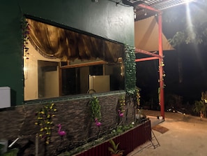 A building with a large window, a stone facade, and a red structure in the background.