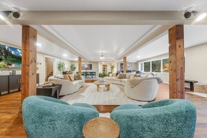 A spacious living area with a large sofa set, a coffee table, and a view of the kitchen and dining area. - Riverfront Sauna! Sunken Hot Tub with river views! (Grantsville)