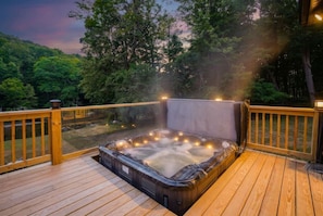 A hot tub on a wooden deck with railings, surrounded by trees. - Riverfront Sauna! Sunken Hot Tub with river views! (Grantsville)