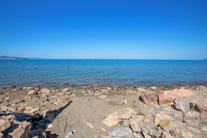 A rocky shoreline with clear blue water and distant land. - Villa Janela Escape & Retreat, 30m From the Beach (Orbetello)