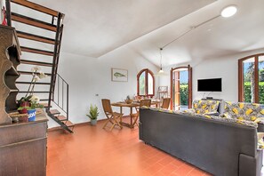 Un grand espace de vie comprenant un canapé, une table à manger, des chaises, un escalier et un téléviseur.