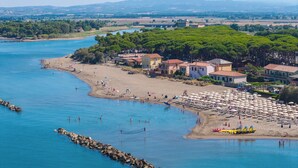 A coastal town with a beach, clear blue waters, and buildings with red roofs.
