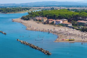 Une ville côtière dotée d’une plage, d’une eau d’un bleu limpide et de bâtiments aux toits rouges.