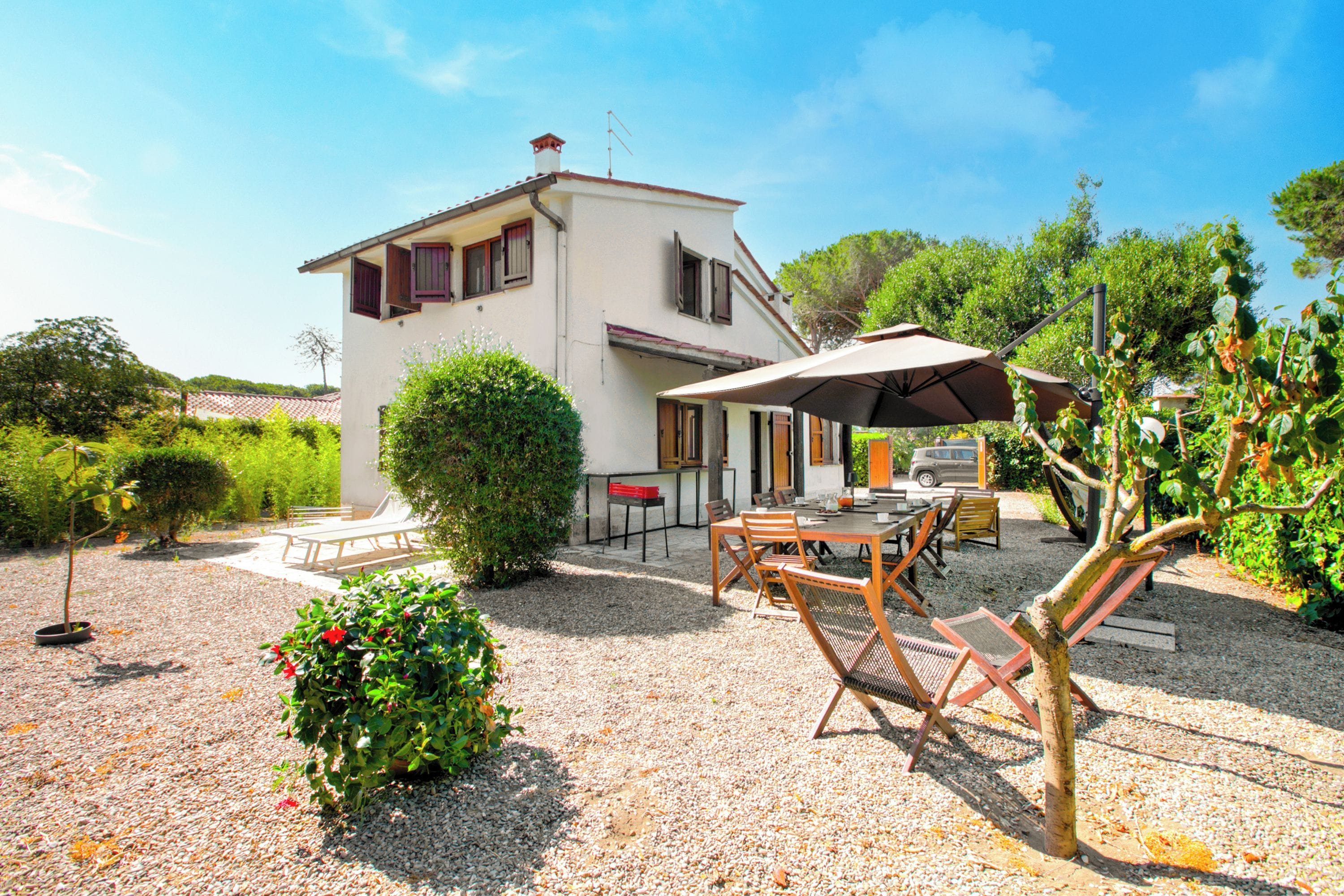 Une maison à deux étages dotée d’un patio comprenant une table, des chaises et un parasol.